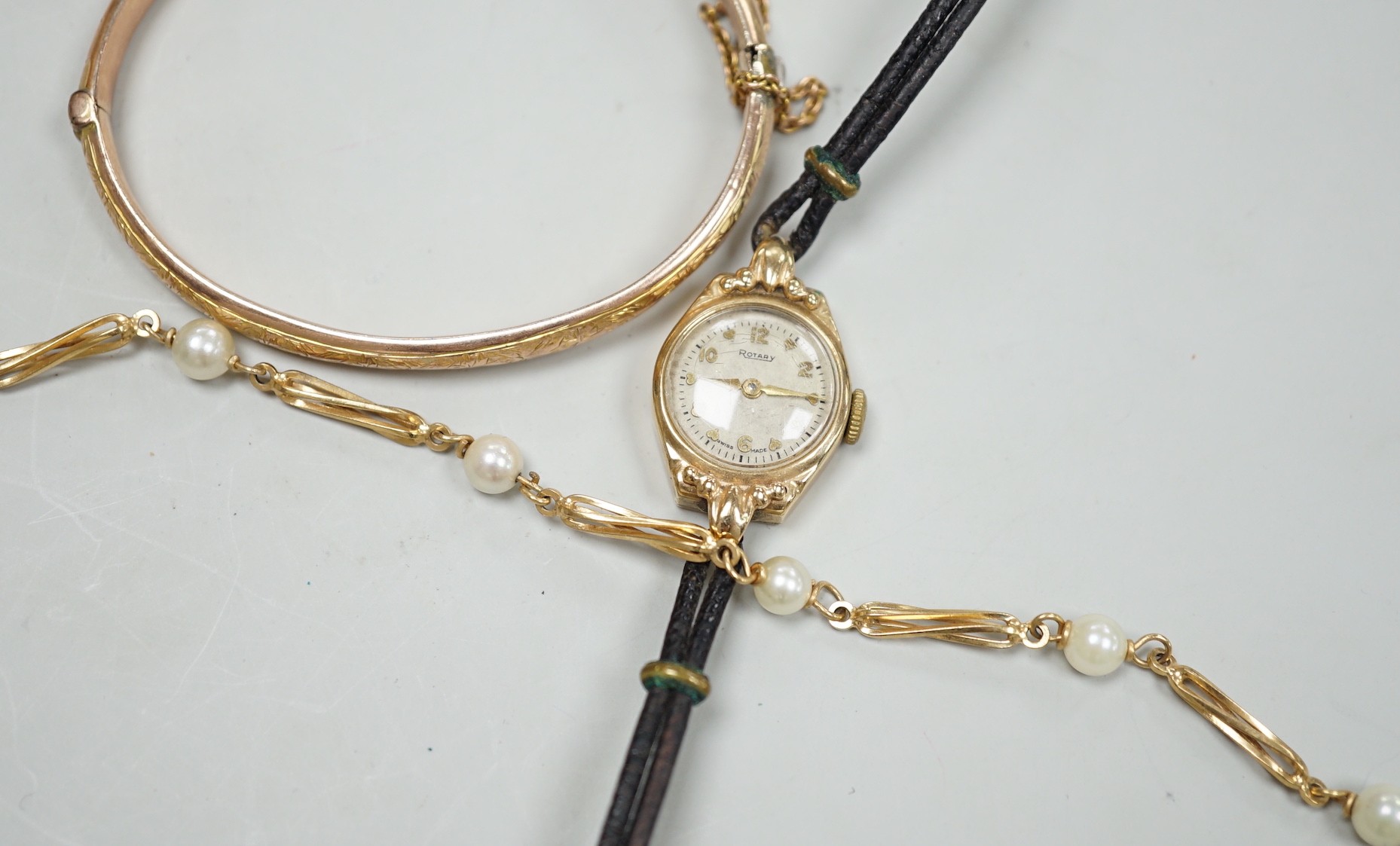 A modern 9ct gold and cultured pearl set bracelet, 18.5cm, a 9ct gold hinged bangle and a lady's yellow metal Rotary wrist watch, gross weight 21.3 grams.